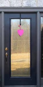 A photo of a door with a paper heart pinned on the front